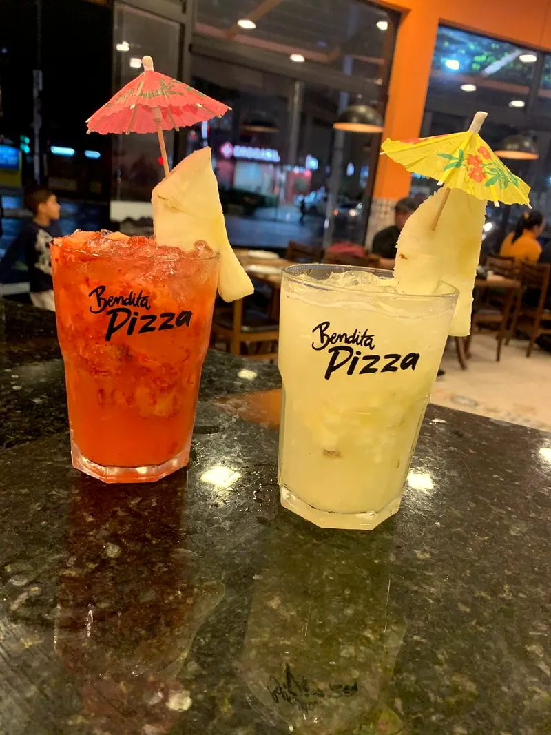 Dois drinks, um vermelho e um de limão, nos copos com a logo da Bendita Pizza